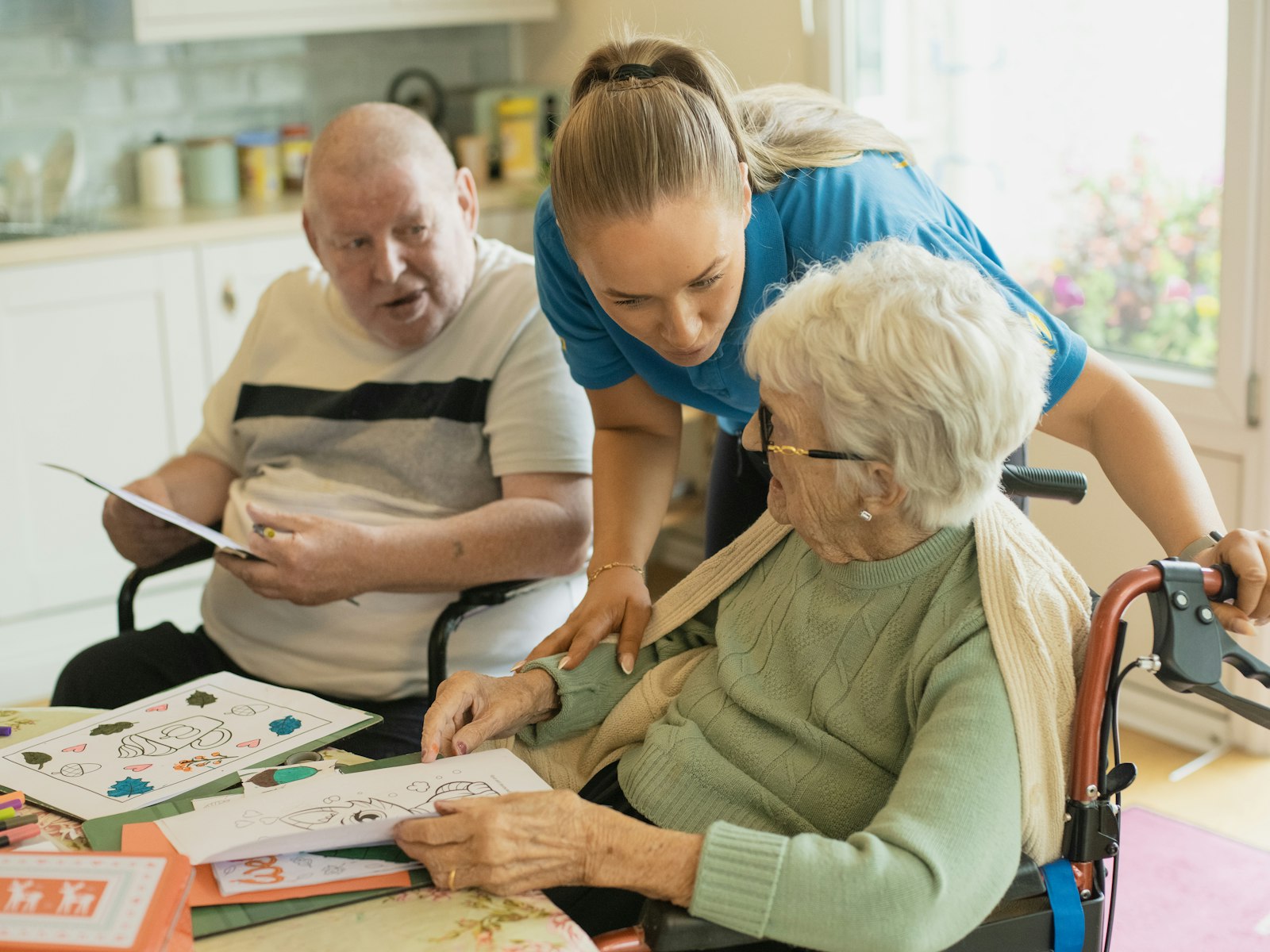 A caregiver helping an older couple at a table